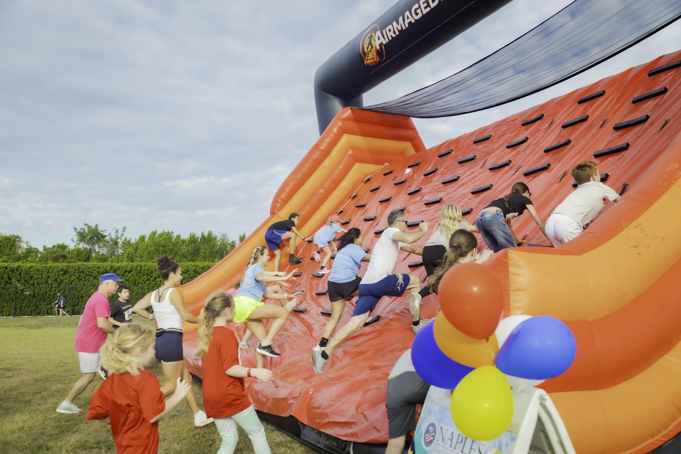 Participants climbing an orange and black inflatable obstacle